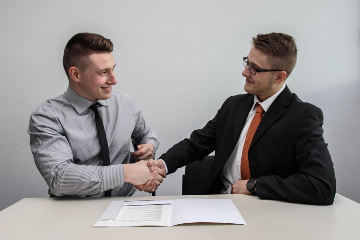 Two business partners shaking hands over a signed agreement